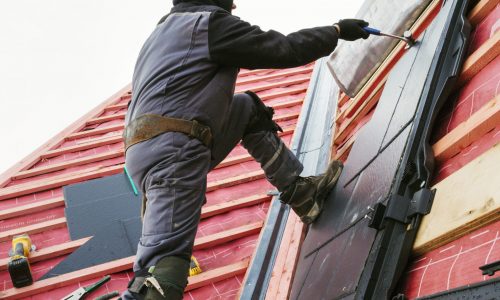 A roofer replacing the tiles on a house roof.